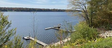 A lakeside view with docked boats, grassy areas, and trees.