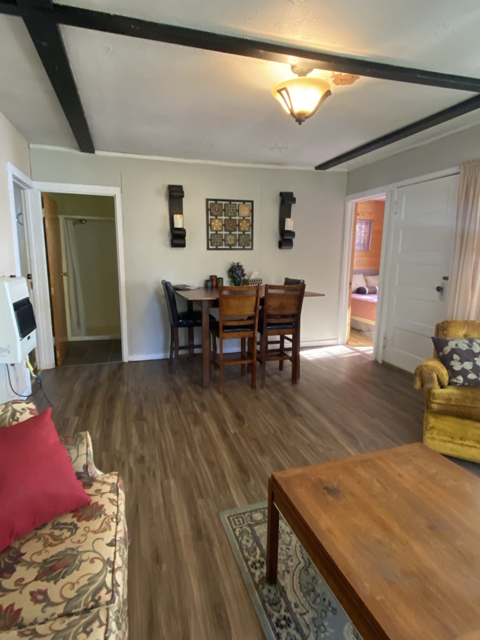 A dining area with a table and chairs, a patterned rug, and a wooden floor.