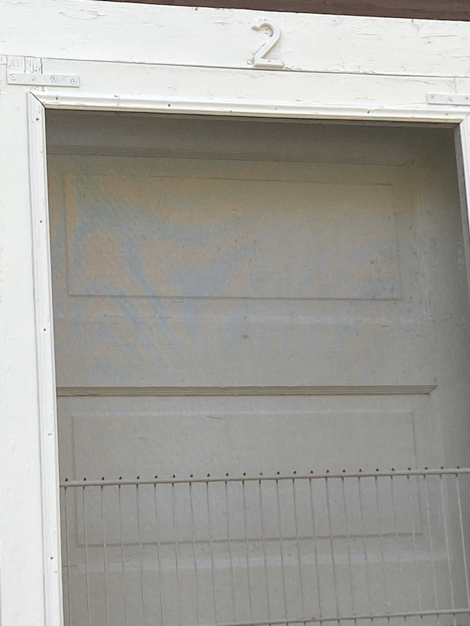 A white door with a number "2" above it and a metal grille at the bottom.