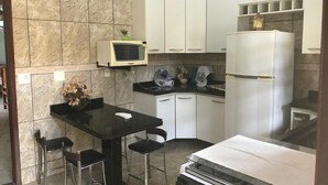 Une cuisine de taille réduite avec des meubles blancs, une table à manger noire et un four à micro-ondes.