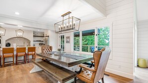 A spacious kitchen with a large dining table, wooden chairs, and a hanging light fixture. - Mountain-view home with high-speed WiFi, wood fireplace, W/D & central AC (Beech Mountain)