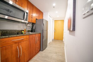 Kitchen features a sink, granite countertop, and stainless steel microwave.