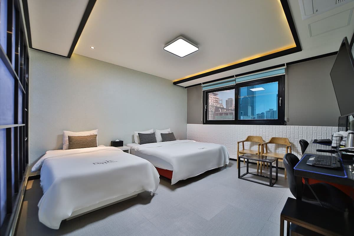 A modern hotel room with two beds, a desk, and a chair.