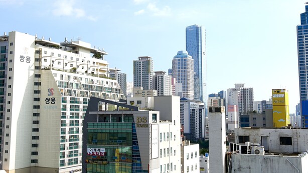 Un paysage urbain avec des immeubles modernes de grande hauteur, dont une tour imposante ornée d’une enseigne.