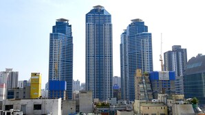 Une vue urbaine mettant en scène trois imposants gratte-ciel, dont l’un se distingue par sa couleur bleue et blanche.