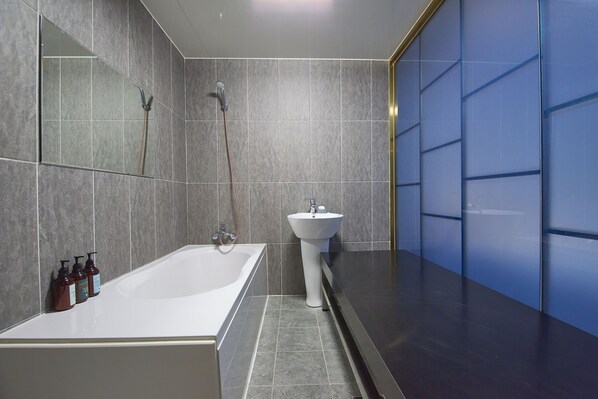 A modern bathroom with a bathtub, a sink, and a shower.