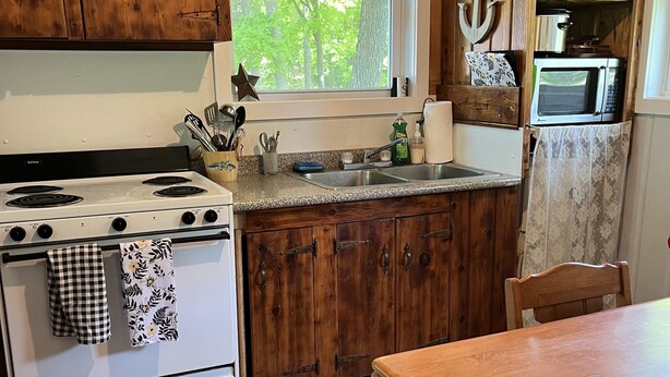 A kitchen with wooden cabinets, a stove, a sink, and a dining table.