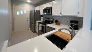 A modern kitchen with white cabinets, stainless steel appliances, a wooden countertop, and a built-in oven. - Birdie`s Bungalow on Fripp/Cards Avail/Golf Cart (Fripp Island)