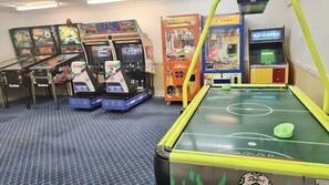 Una stanza con diversi giochi arcade, tra cui 'Segafredo' e '60 Games', e un tavolo da biliardo.