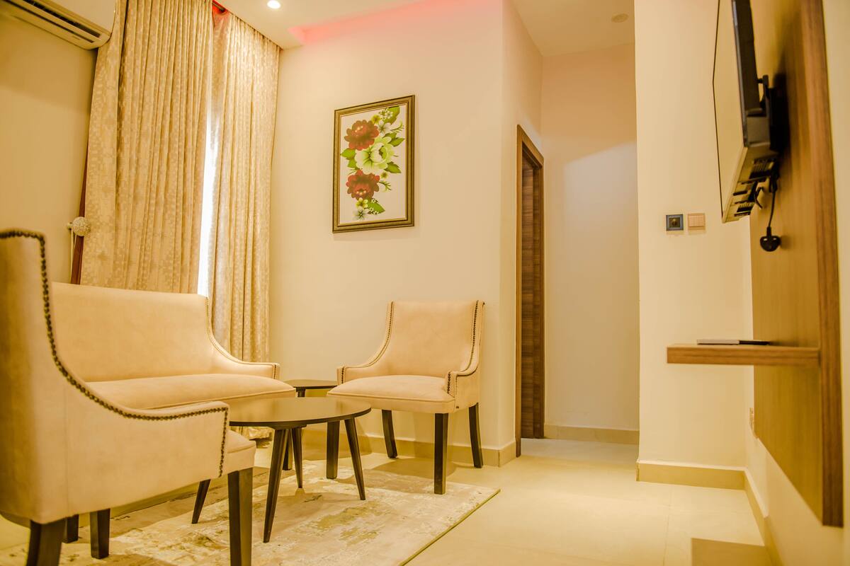 A living room with two armchairs, a small table, and a decorative wall piece.