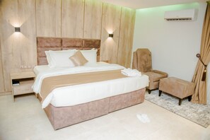 Une chambre dotée d’un grand lit, de tables de chevet, d’une chaise et d’un appareil de climatisation.