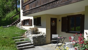 A two-story building with a stone staircase leading to a wooden deck. - Am Sonnenhang by Interhome (Churwalden)