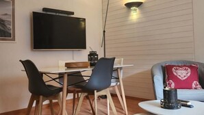 A modern living room with a flat-screen TV, a dining table with chairs, a coffee table, and a sofa with a heart-patterned pillow. - Am Sonnenhang by Interhome (Churwalden)