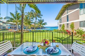 A dining table with a view of the ocean and palm trees.