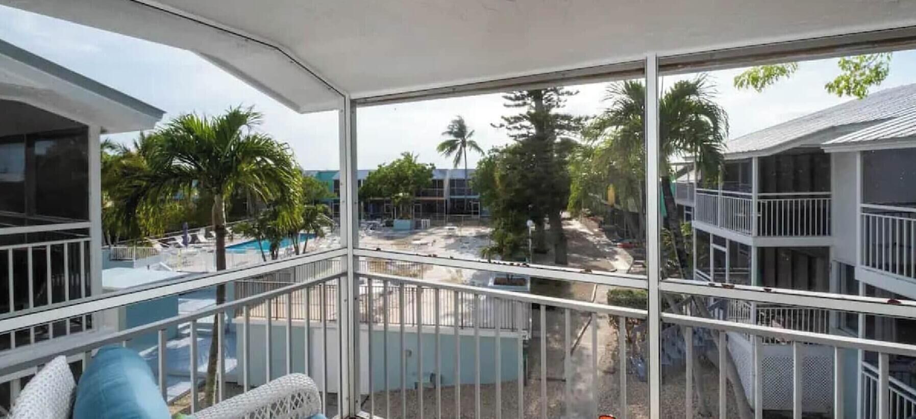 A balcony with a view of a pool and palm trees.