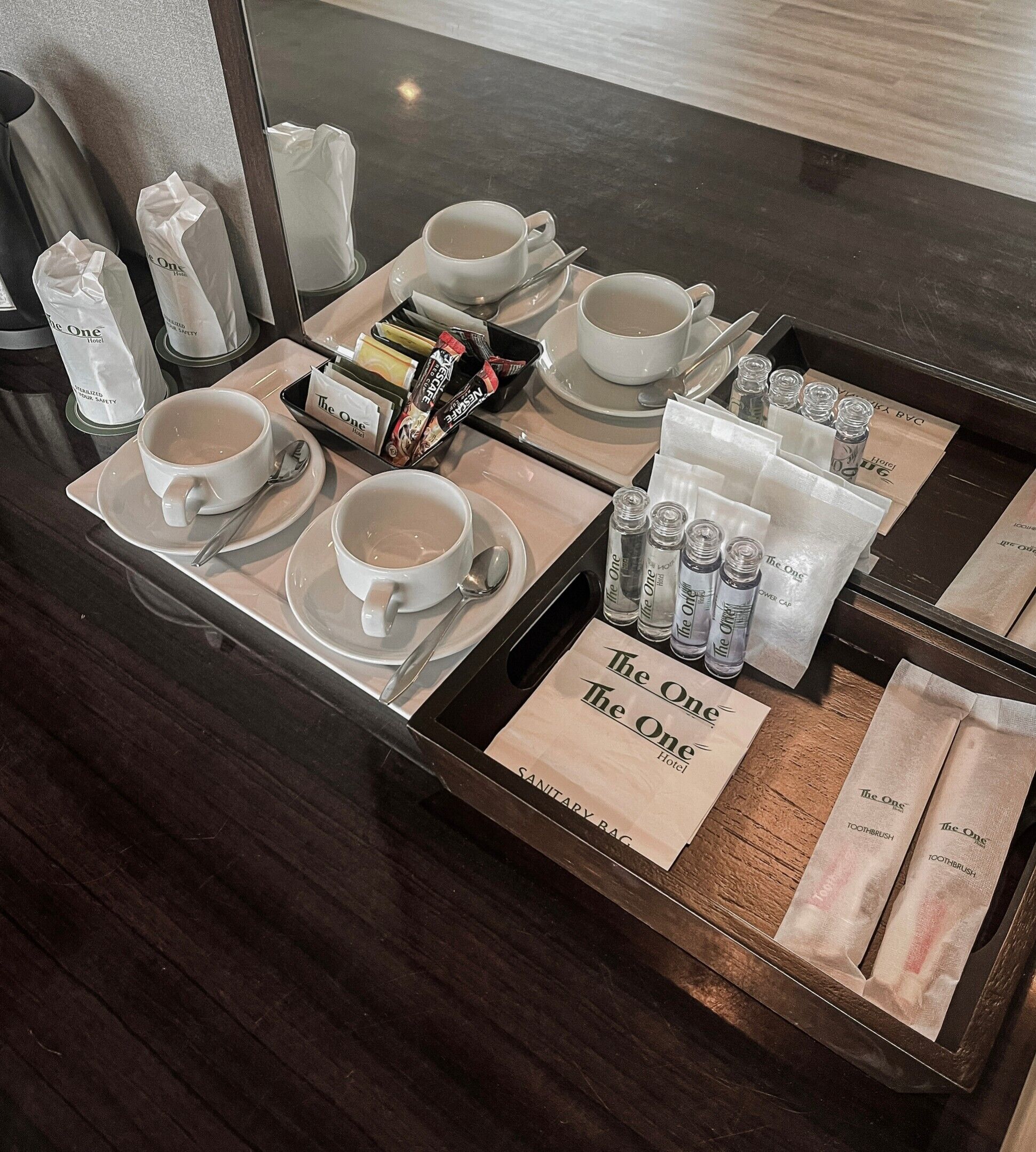 Ein Frühstückswagen im Hotelzimmer mit Tassen, einer Kaffeekanne, Teebeuteln und Toilettenartikeln.