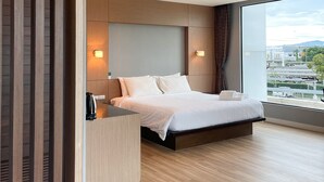Quarto de hotel moderno com uma cama grande, divisória de madeira e vista para a cidade.