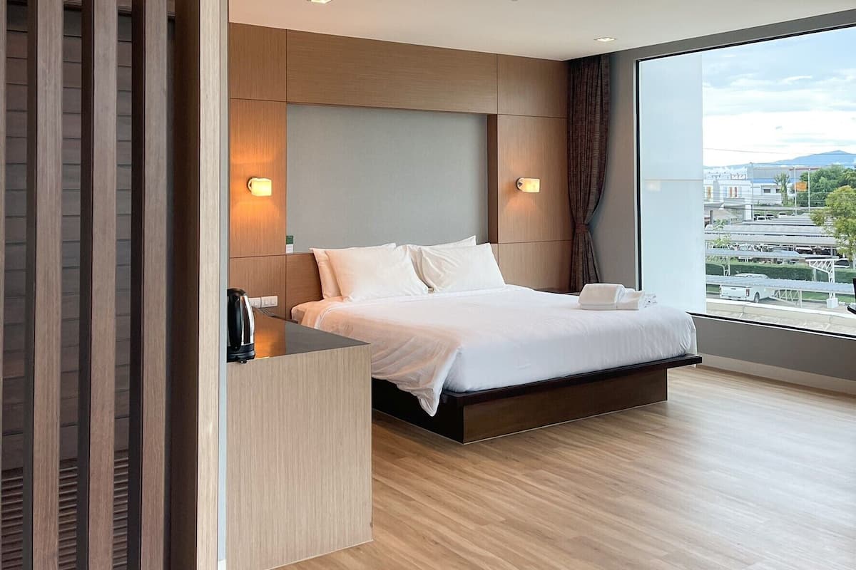 Una habitación de hotel moderna con una cama grande, un separador de madera y vistas a la ciudad.