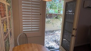 A dining area with a round wooden table and a ceiling light fixture. - Room 6️⃣ with kitchen and bathroom in Old Palm Springs hotel by the heated pool 🦋 (Palm Springs)