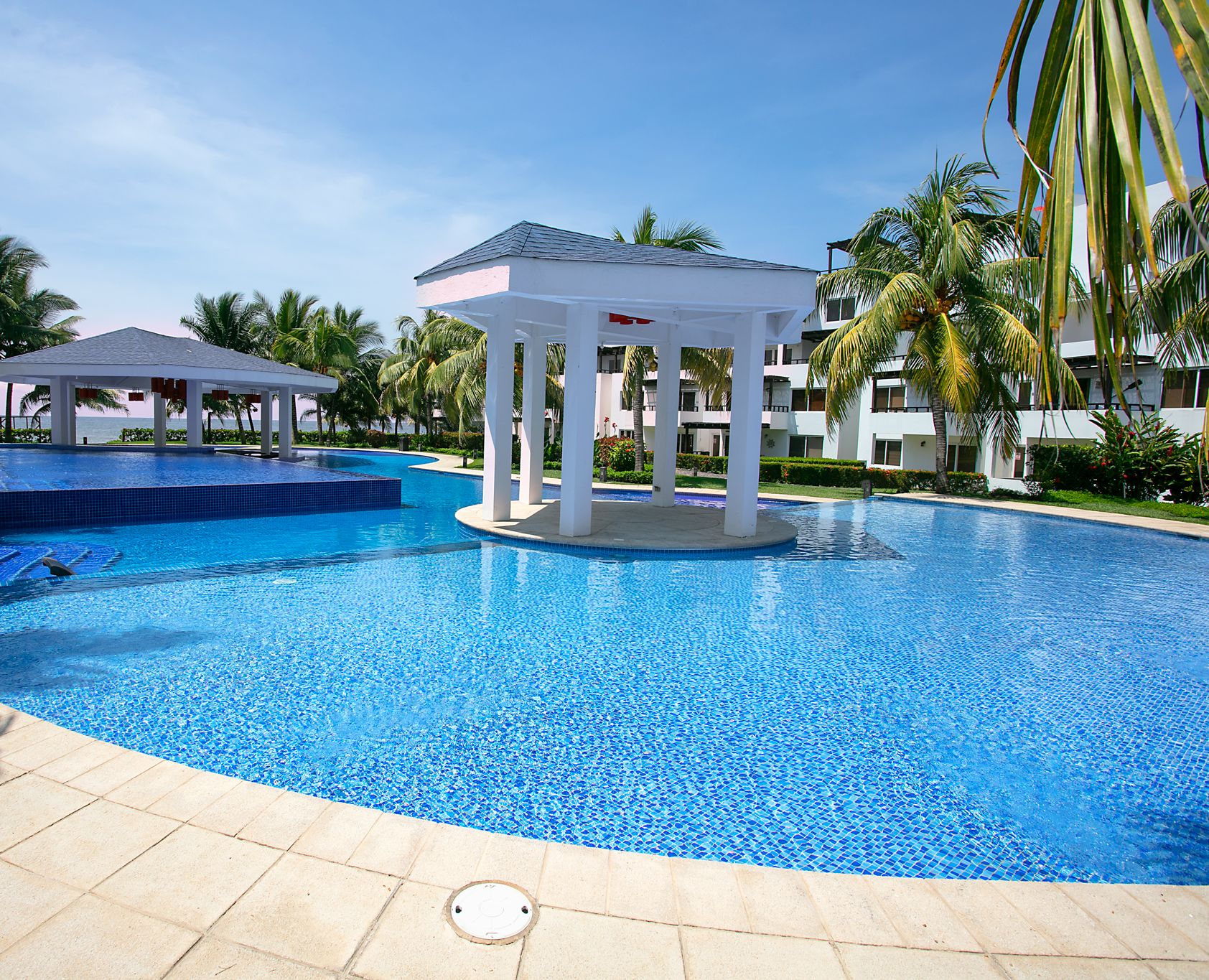 Una piscina con un pabellón y palmeras.