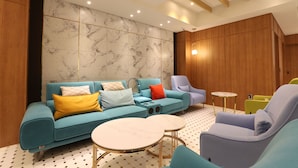 A modern living room with a sectional sofa, armchairs, and a coffee table. - H Avenue Hotel (Busan)