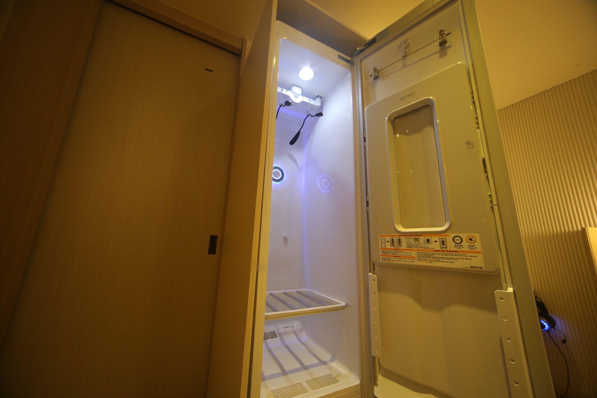 Una ducha compacta con acceso directo, panel de control en la puerta, repisa interior y un pequeño respiradero en la parte inferior.