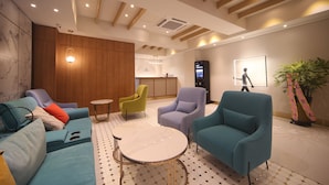 A modern lobby with seating areas, a reception desk, and a digital check-in kiosk. - H Avenue Hotel (Busan)