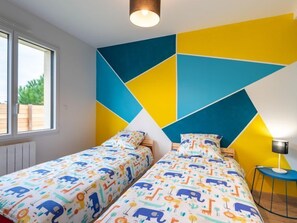 Makuuhuoneessa on kaksi sänkyä, geometriset seinätaideteokset ja ikkuna, josta avautuu näkymä vehreään maisemaan.