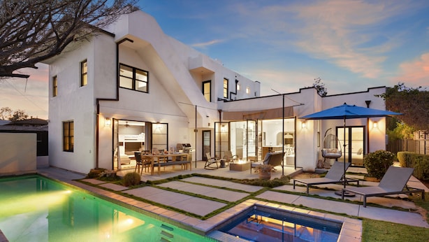 A modern house with a swimming pool, outdoor seating, and a well-lit patio area.