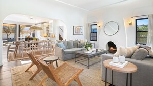 A spacious living room with a fireplace, a dining area, and a kitchen visible through an archway.