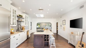 A spacious kitchen with white cabinetry, a central island, and a wooden floor.