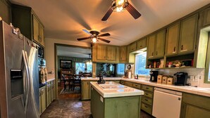 A kitchen with a central island, a refrigerator, and a ceiling fan.