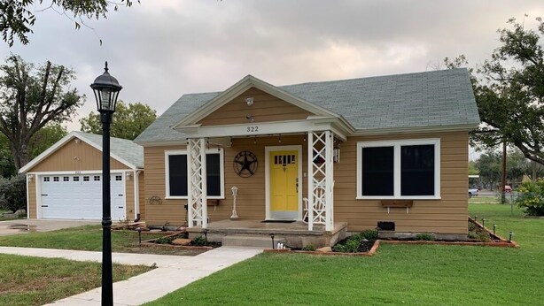 A two-story house with a front porch, a garage, and a well-maintained lawn.