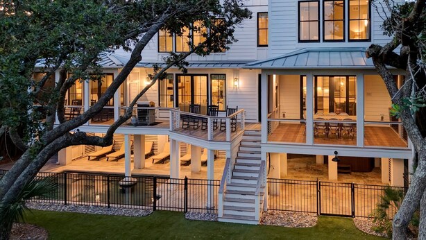 A modern two-story house with a covered deck, outdoor seating, and a staircase leading to the upper level. - Discounts! OCEANFRONT STUNNER- Discounted Rates! Pool, Hot Tub, Elevator (Isle Of Palms)