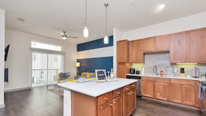 A modern kitchen with wooden cabinets, a white countertop, and a central island. - Downtown Retreat Near Attractions W\ Free Parking (Houston)