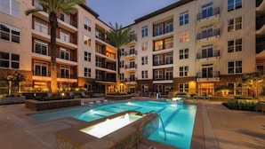 A multi-story hotel with a swimming pool, palm trees, and outdoor seating areas. - Downtown Retreat Near Attractions W\ Free Parking (Houston)