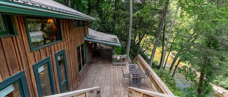 A wooden deck with a staircase leading to a cabin surrounded by dense forest.