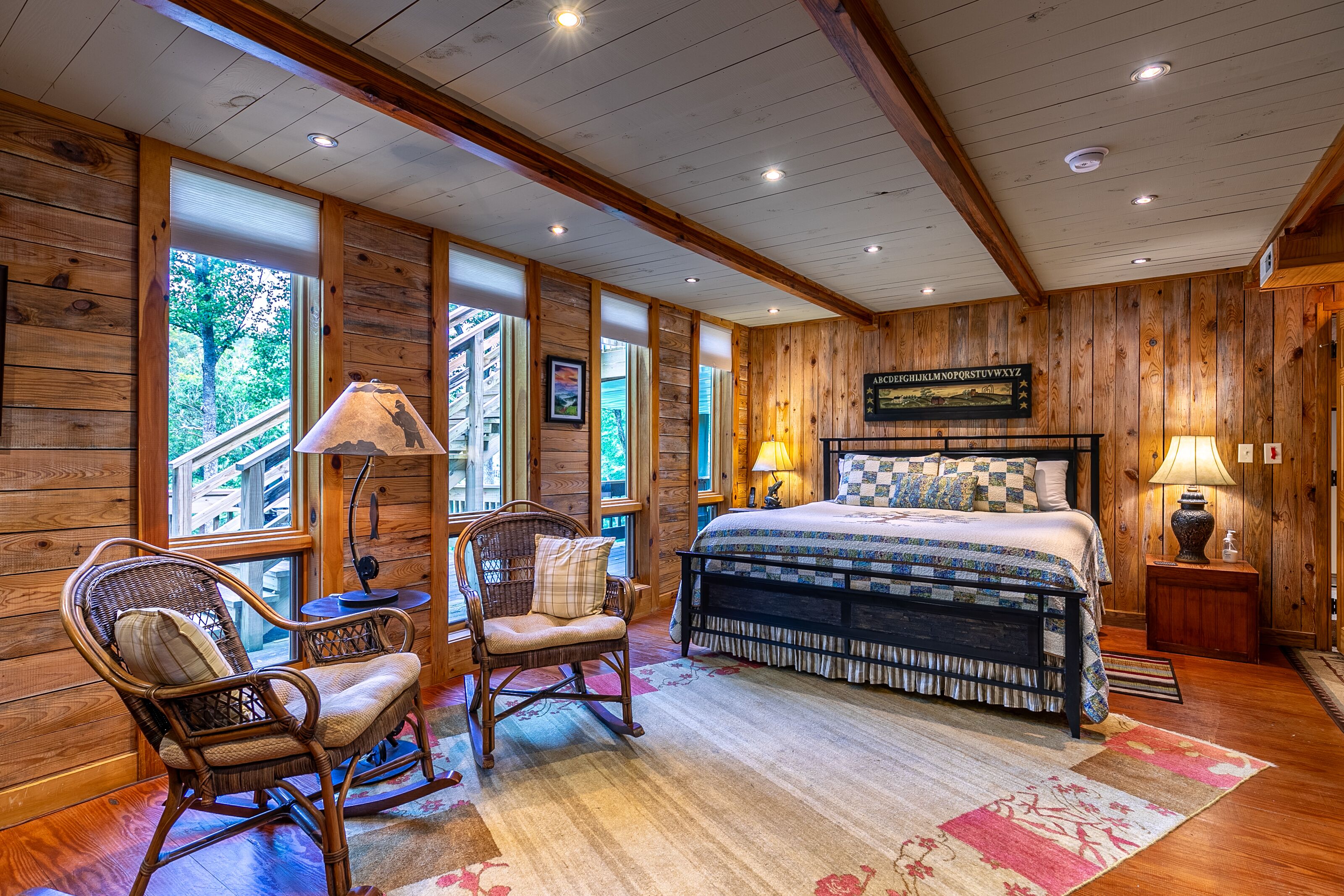 Cozy wood-paneled retreat at A River Mist, where rocking chairs by the windows invite a quiet morning among the treetops.
