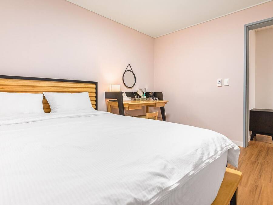 Habitación de hotel ordenada con una cama grande, un escritorio de madera y una pequeña silla.