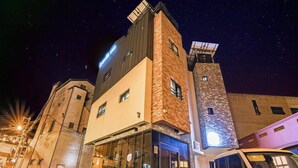 Un edificio moderno con fachada de vidrio y torre de ladrillo, con un coche estacionado en la entrada.