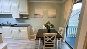 Een eetgedeelte met een tafel, stoelen, een potplant en uitzicht op buiten.