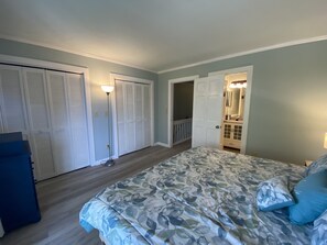 Une chambre à coucher comprenant un lit, une armoire, une salle de bain et un couloir.