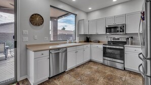 A modern kitchen with white cabinets, stainless steel appliances, and a large window. - Dive Into Spring in Mesa | Community Pool, Hot Tub, Tennis & Hoops (Mesa)
