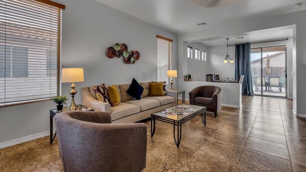 A spacious living room with a sofa, armchair, and coffee table. There is a kitchen area with a dining table and chairs visible through an open door. - Dive Into Spring in Mesa | Community Pool, Hot Tub, Tennis & Hoops (Mesa)