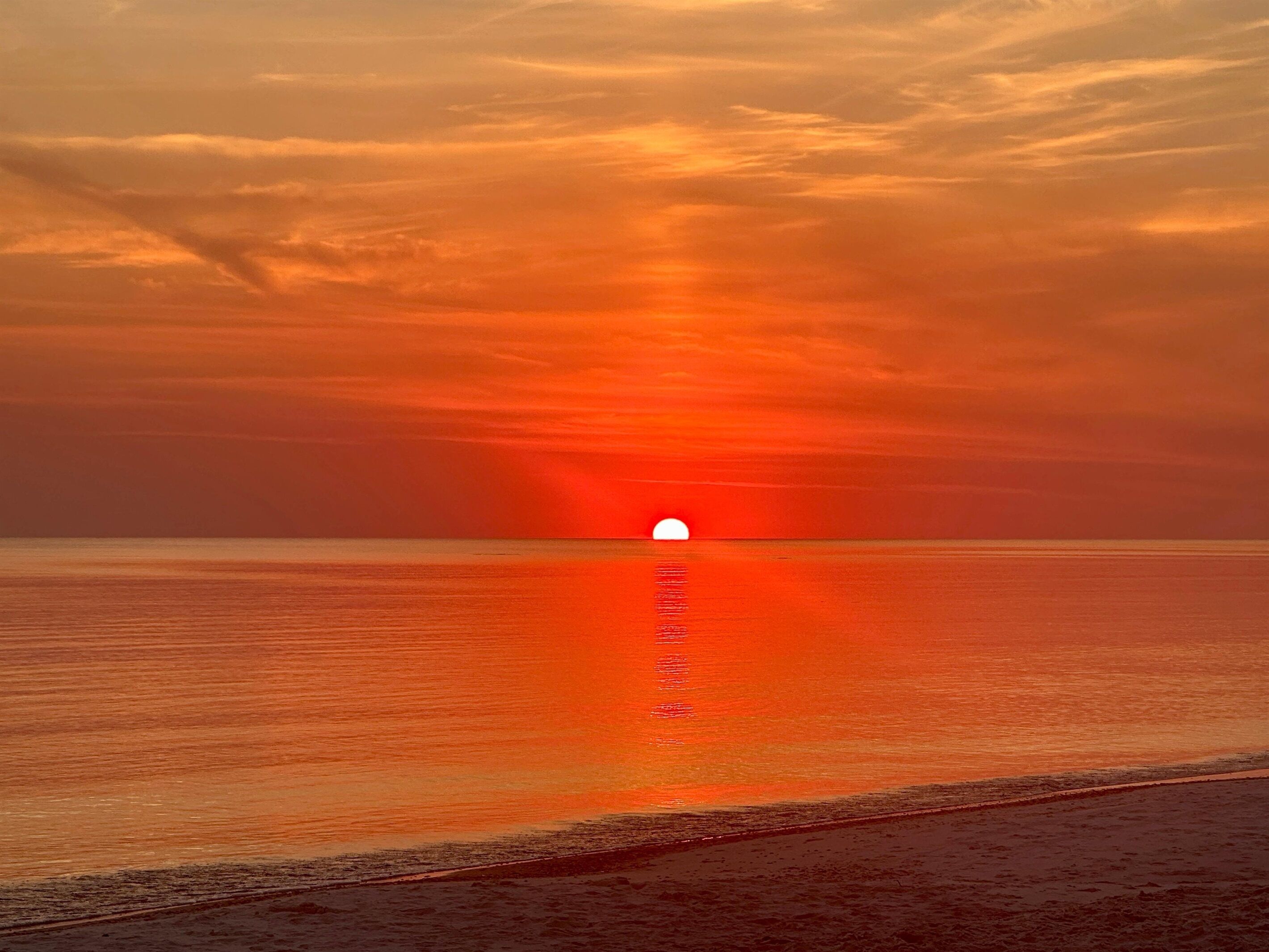 A sunset over a calm sea with a visible horizon line.