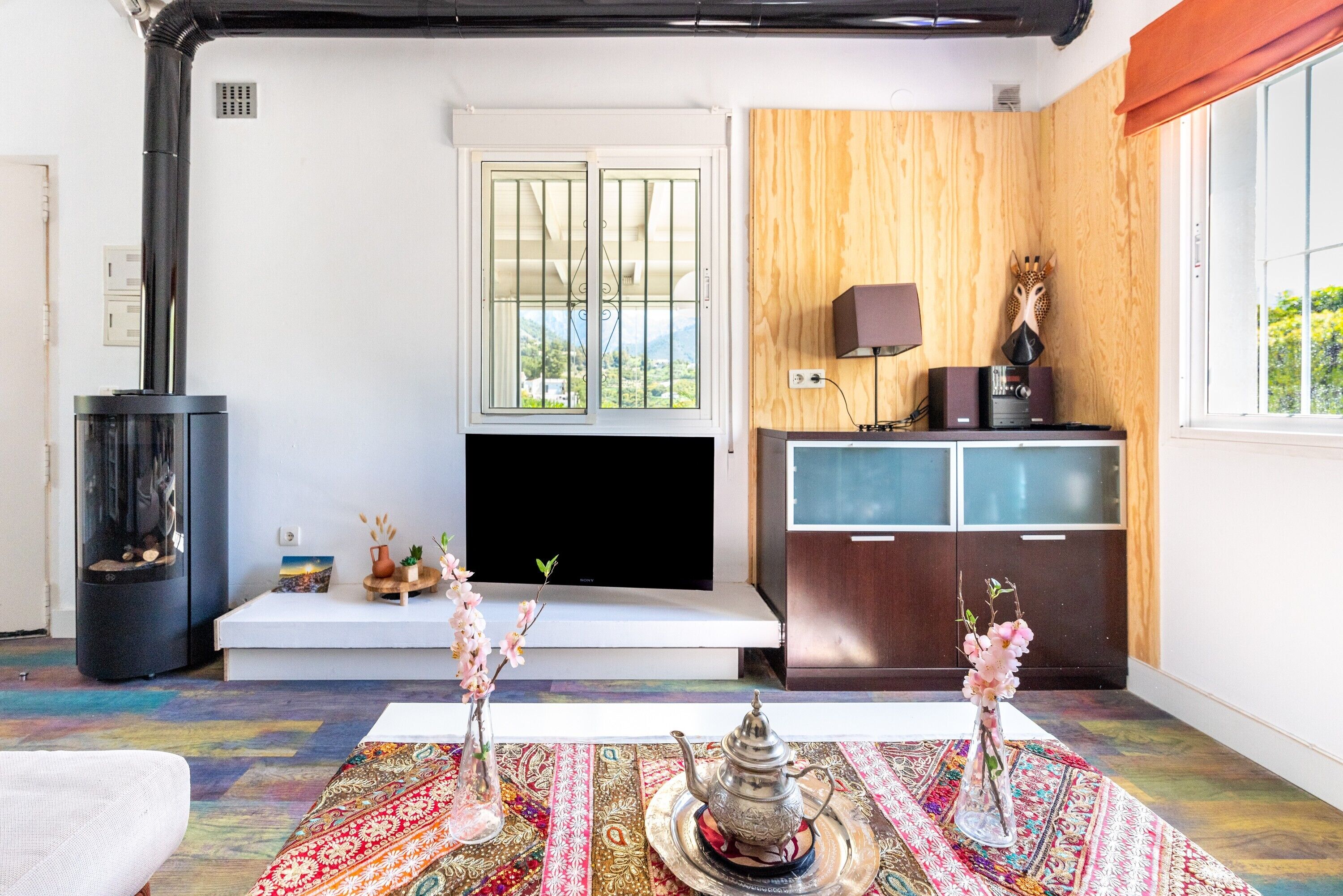 Un salon avec une cheminée, un téléviseur, un mur en bois et une fenêtre donnant sur un beau paysage.