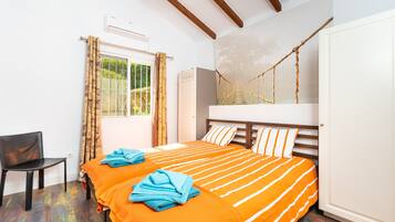 A room with two beds, a chair, a window with curtains, and a hammock.