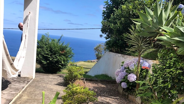 A garden with a view of the sea, a hammock, and various plants. - Pet-Friendly Villa Azores SunriseHouse with Sea View, Pool, Jacuzzi, Wi-Fi, Terrace & Garden (Pedreira)