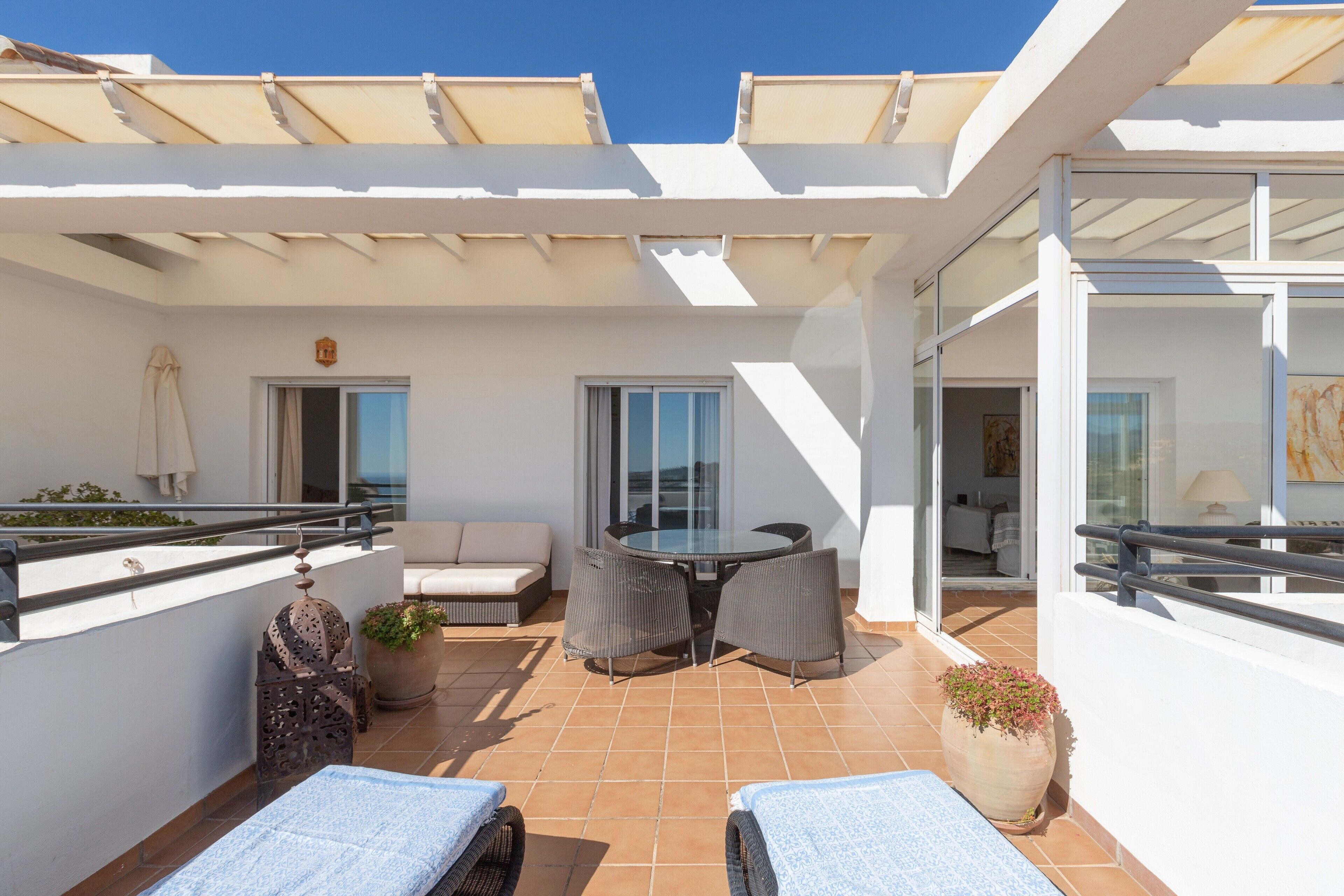 A balcony with a table and chairs, a sofa, and a potted plant.