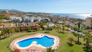 A swimming pool surrounded by greenery, with buildings in the background and a clear view of the sea. - Penthouse with a fantastic view, Mountain View, Sea View, Terrace & Garden (La Cala de Mijas)